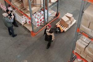 Workers pulling shipping boxes through a warehouse